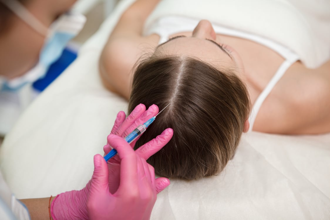 Prfoessional cosmetician giving hairloss treatment scalp injections to female client